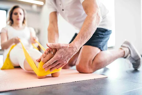 Unkenntlicher leitender Physiotherapeut, der mit einer Patientin arbeitet